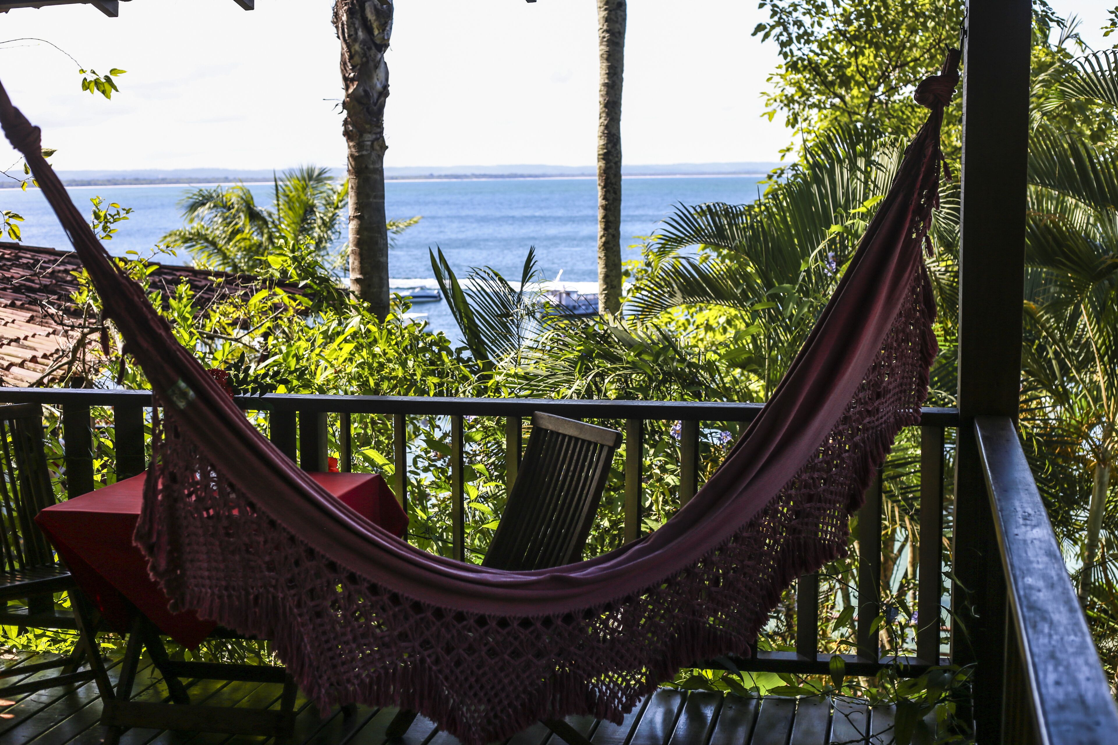 A hammock on a wooden deck with a view of the ocean.