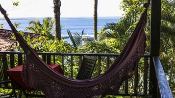 A hammock on a wooden deck with a view of the ocean.