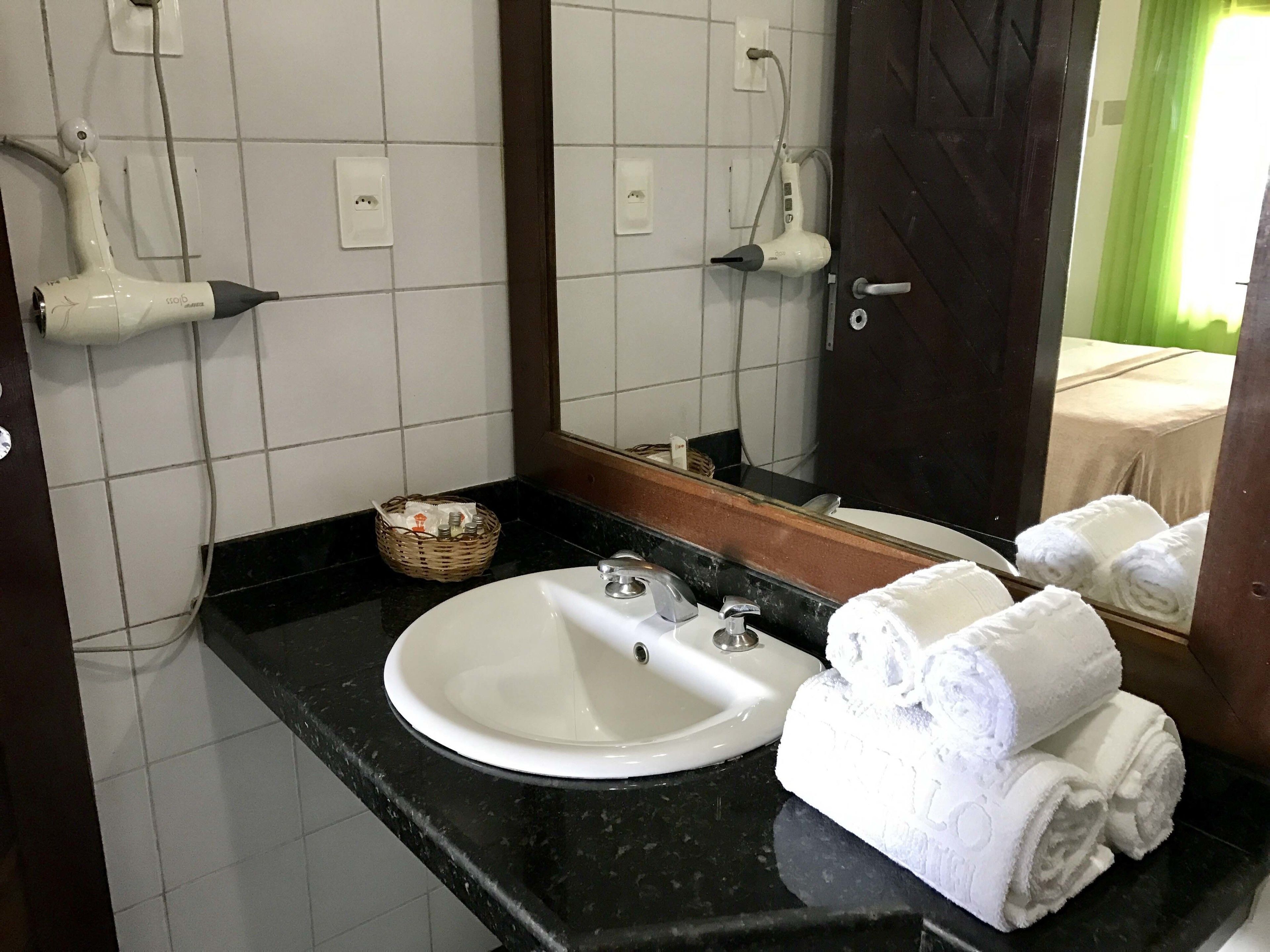 A bathroom with a white sink, a mirror, and a towel rack.