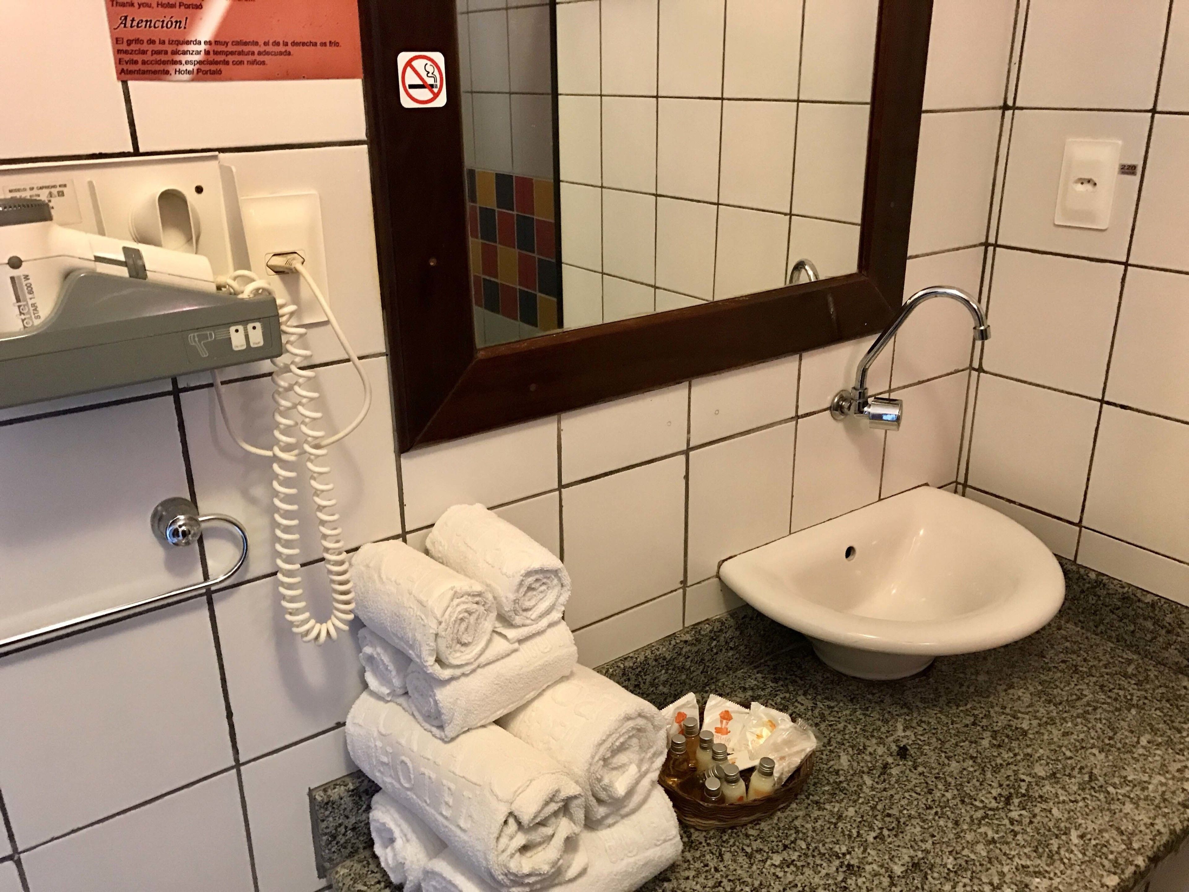 Une salle de bain équipée d’un lavabo, d’un miroir, d’un téléphone et d’une pile de serviettes.