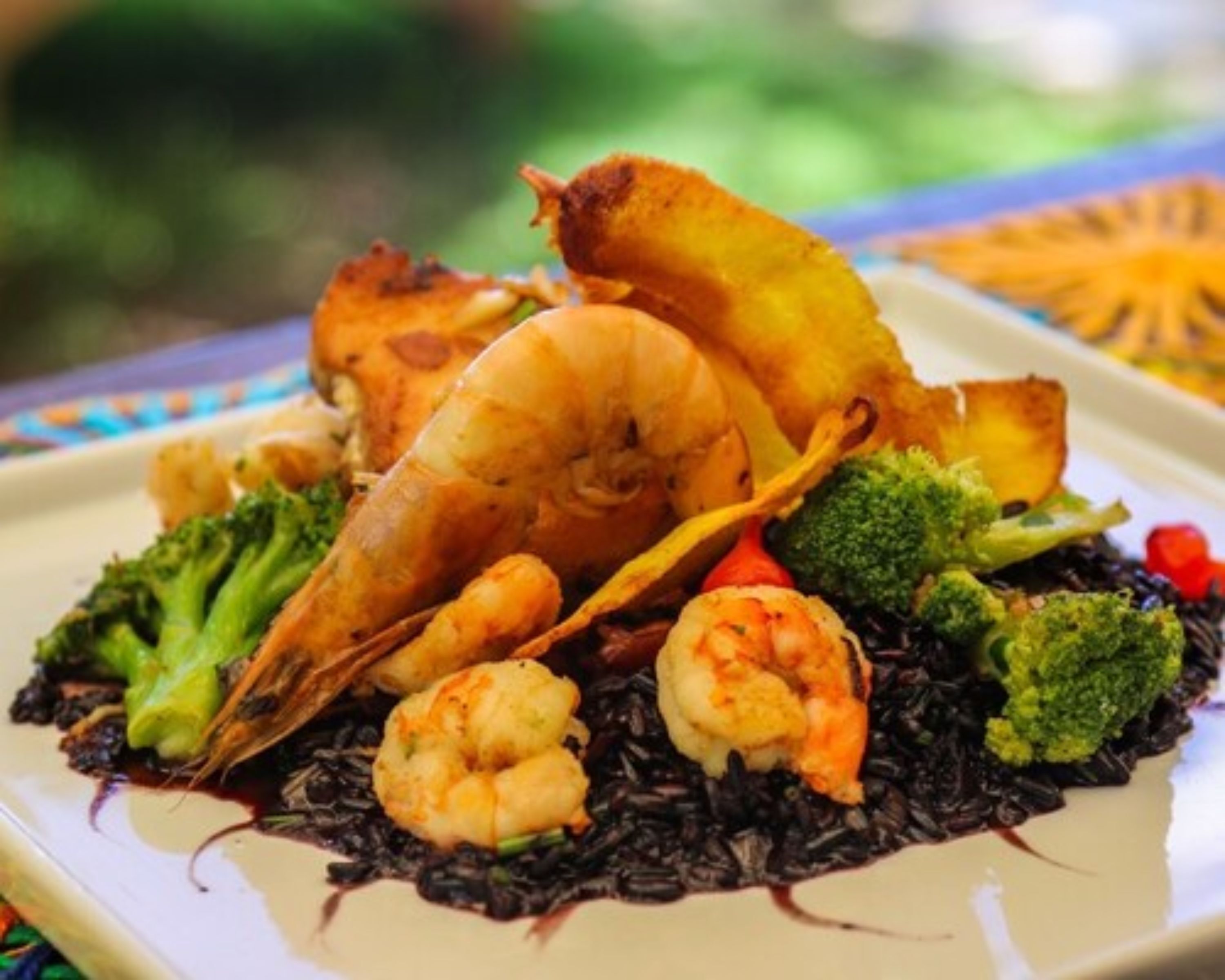 A plate of black rice with shrimp and vegetables.