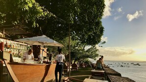 A seaside bar with outdoor seating and a view of the ocean. - Hotel Portaló (Cairu)