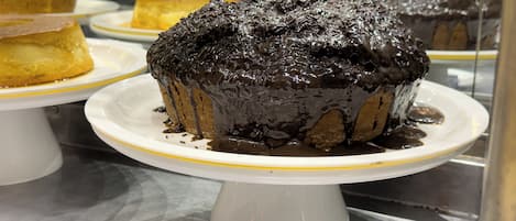 Un pastel de chocolate sobre un plato blanco, con un cartel que dice 'Bolo de Chocolate'.