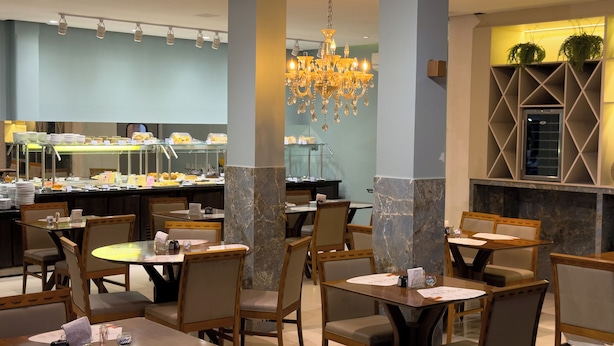 Un restaurante con pilares de mármol, candelabros y una zona de bufé.