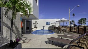A pool area with lounge chairs, a small pool, and a seating area with umbrellas. - Marinas Maceió Hotel (Maceió)