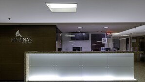 A reception area with a modern design, featuring a marble counter and a logo for 'MARINAS Maceio Hotel'. - Marinas Maceió Hotel (Maceió)