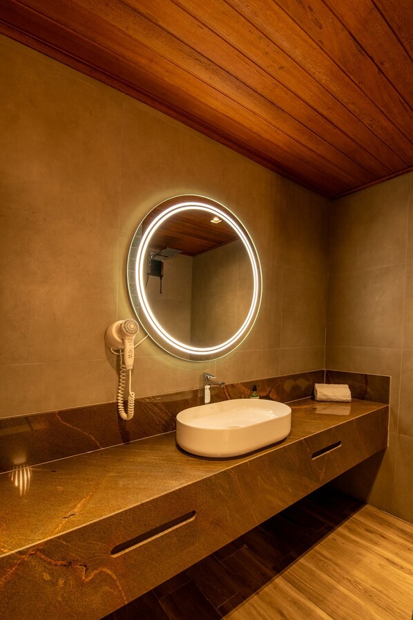 Une salle de bain avec un miroir rond, un lavabo et un sèche-cheveux.