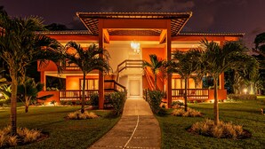 Un hotel con entrada central, un paseo cubierto y palmeras.