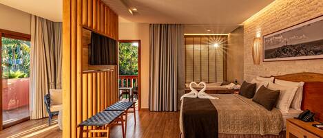 Una habitación de hotel moderna con una cama grande, muebles de madera, un televisor y un balcón con cortinas.