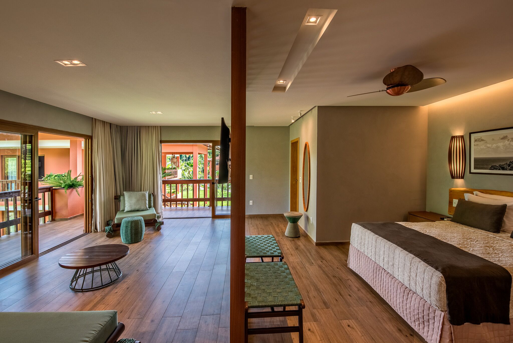 Habitación de hotel moderna con una cama grande, un área de descanso con mesa y sillas, y un balcón con vistas.
