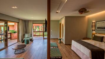 Habitación de hotel moderna con una cama grande, un área de descanso con mesa y sillas, y un balcón con vistas.