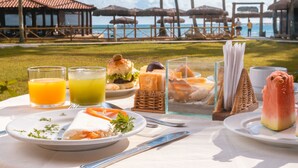 Una mesa lista para el desayuno con vista a la playa y al océano.