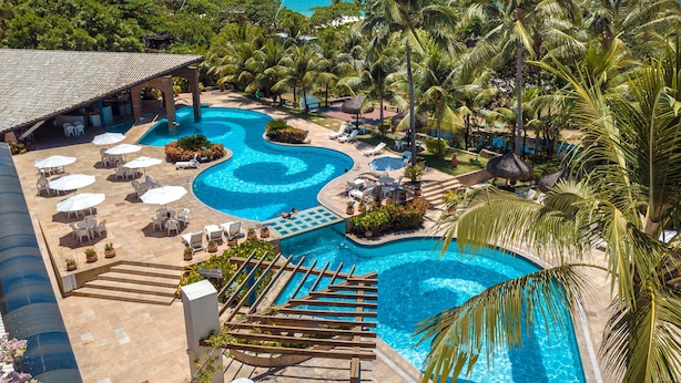 A resort with multiple swimming pools, lounge areas, and palm trees.