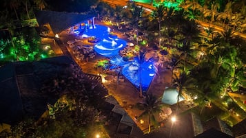 A resort with a central pool, outdoor seating, and palm trees.