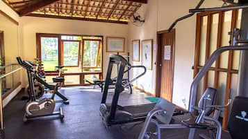 A gym with exercise equipment, large windows, and a wooden ceiling.