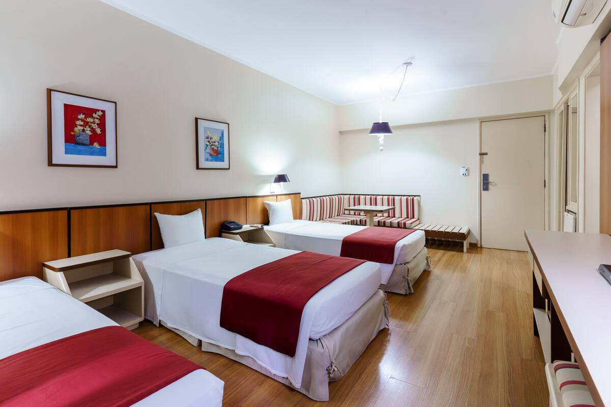 Ein Hotelzimmer mit zwei Betten, einem Schreibtisch, einem Stuhl und einem kleinen Tisch.
