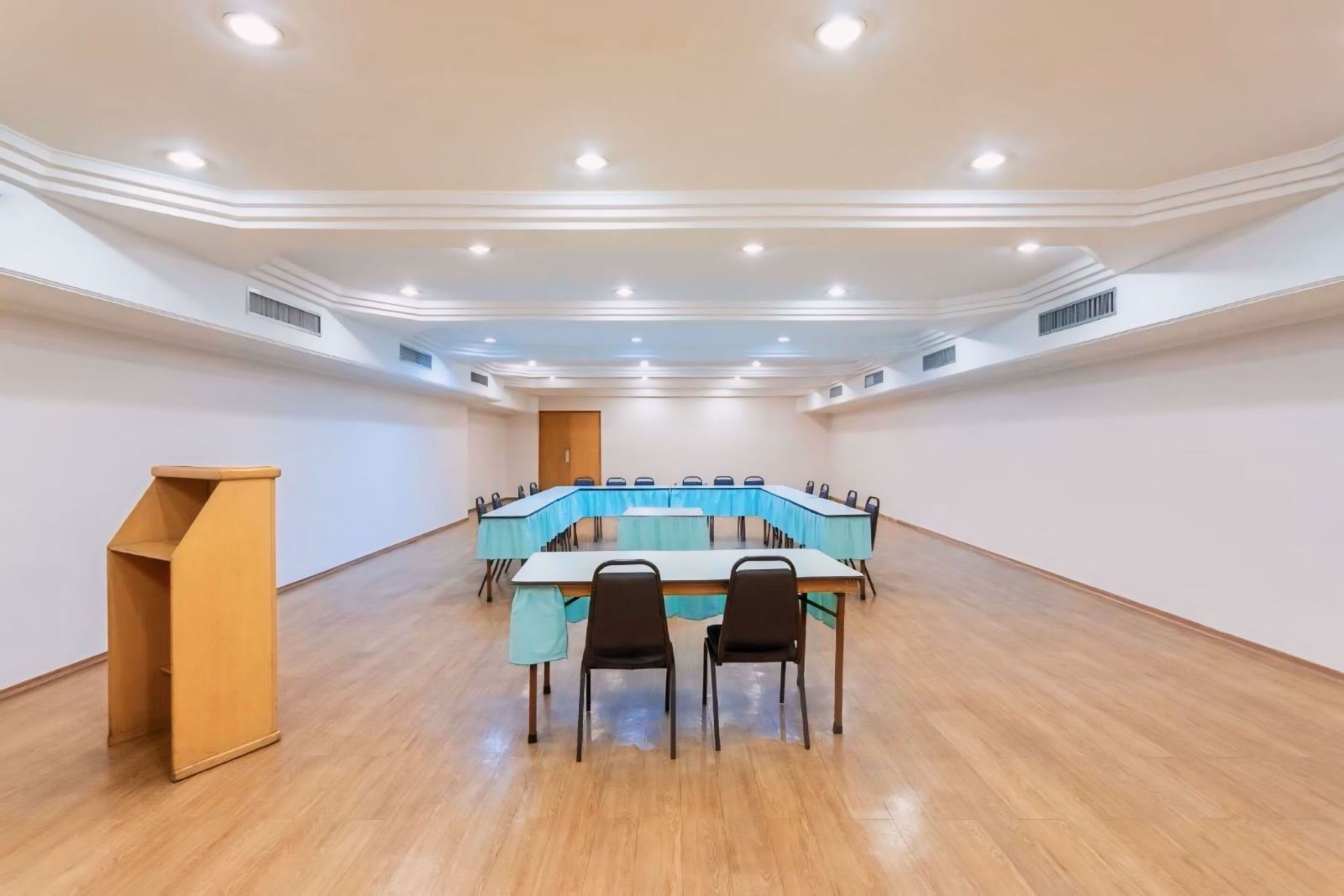 Un salón de conferencias con una larga mesa, dos sillas y un atril.
