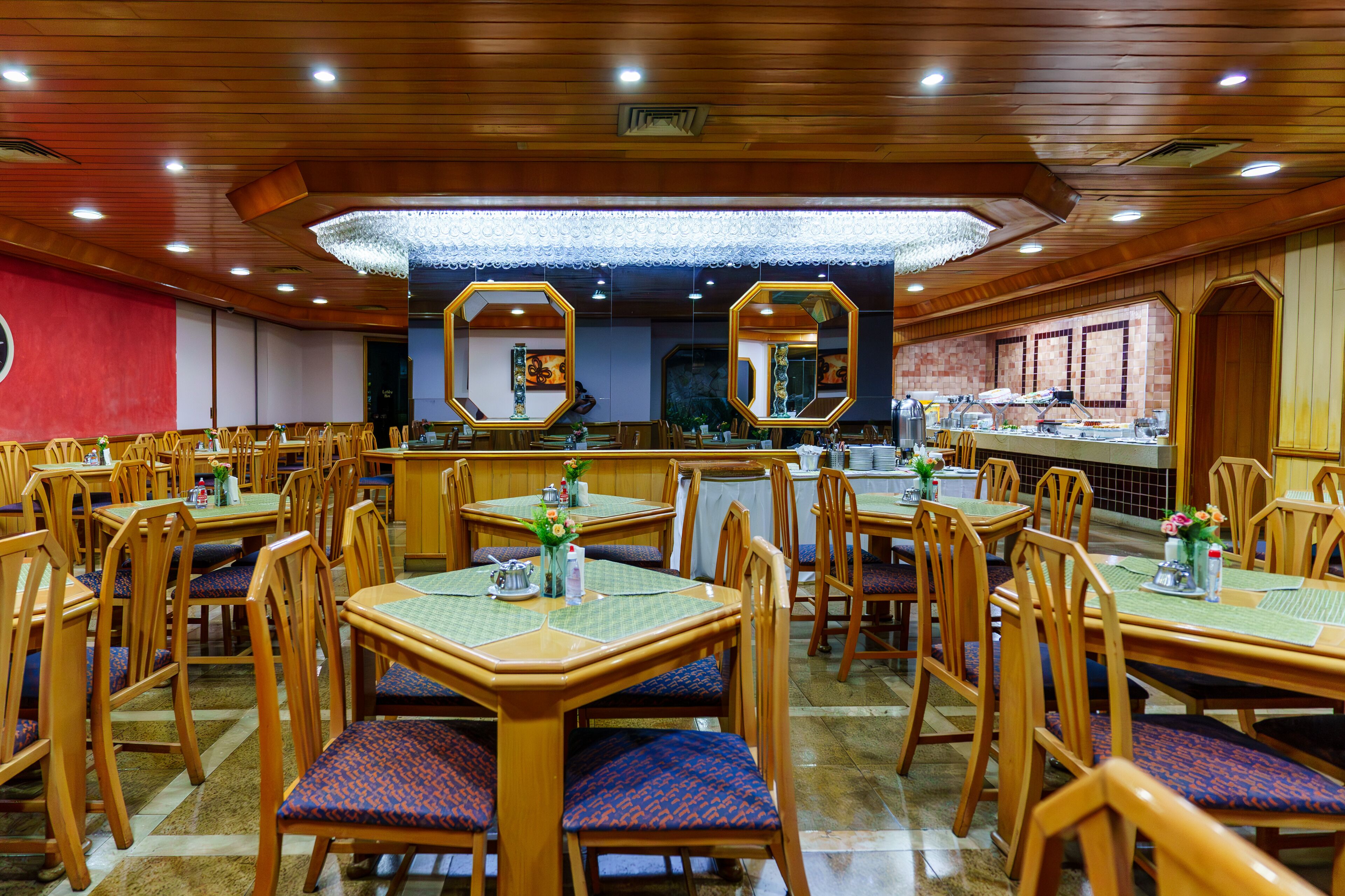 Een restaurant met houten tafels en stoelen, een betegelde vloer en een bakstenen muur.