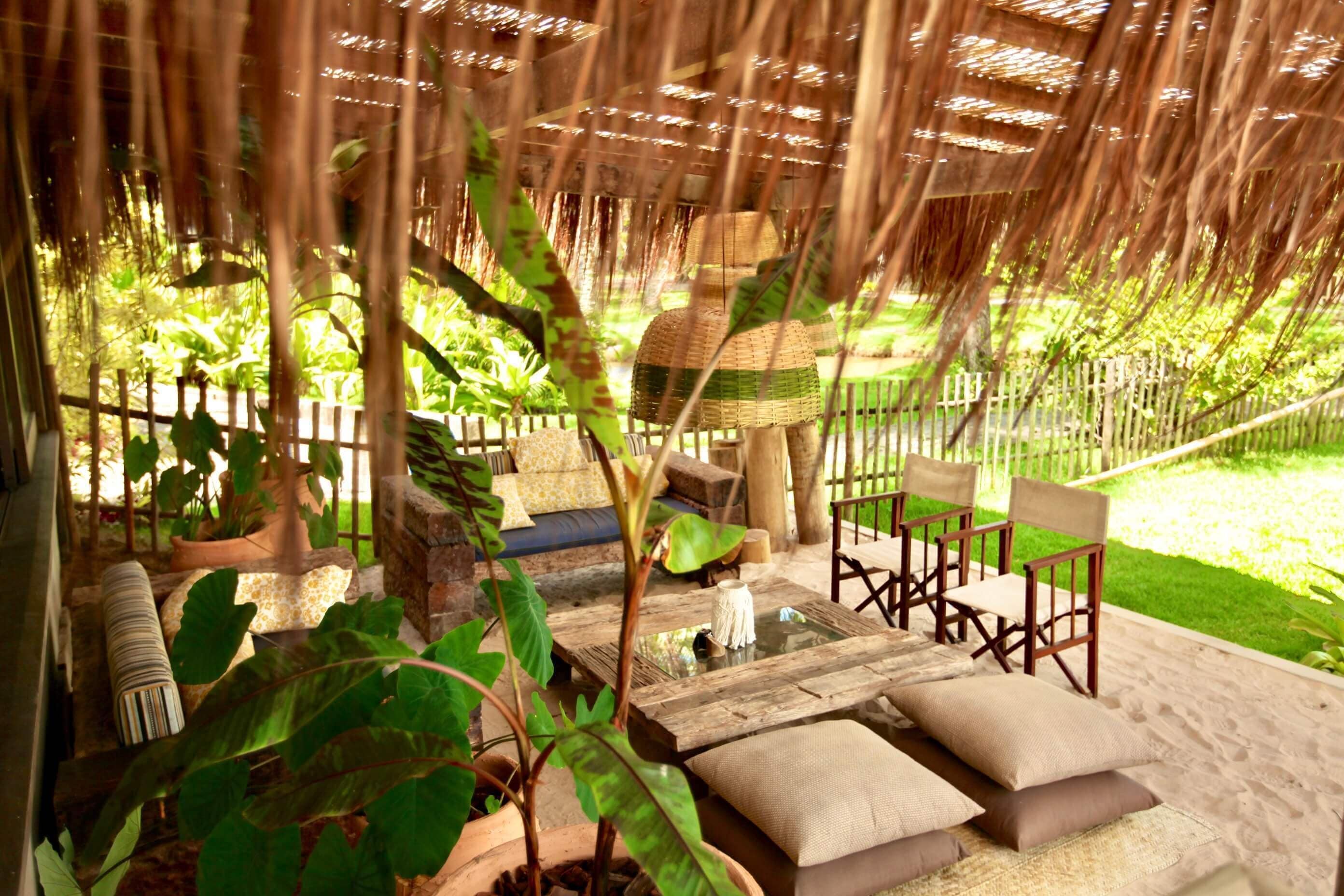 A covered outdoor seating area with a wooden table, chairs, and a sofa.