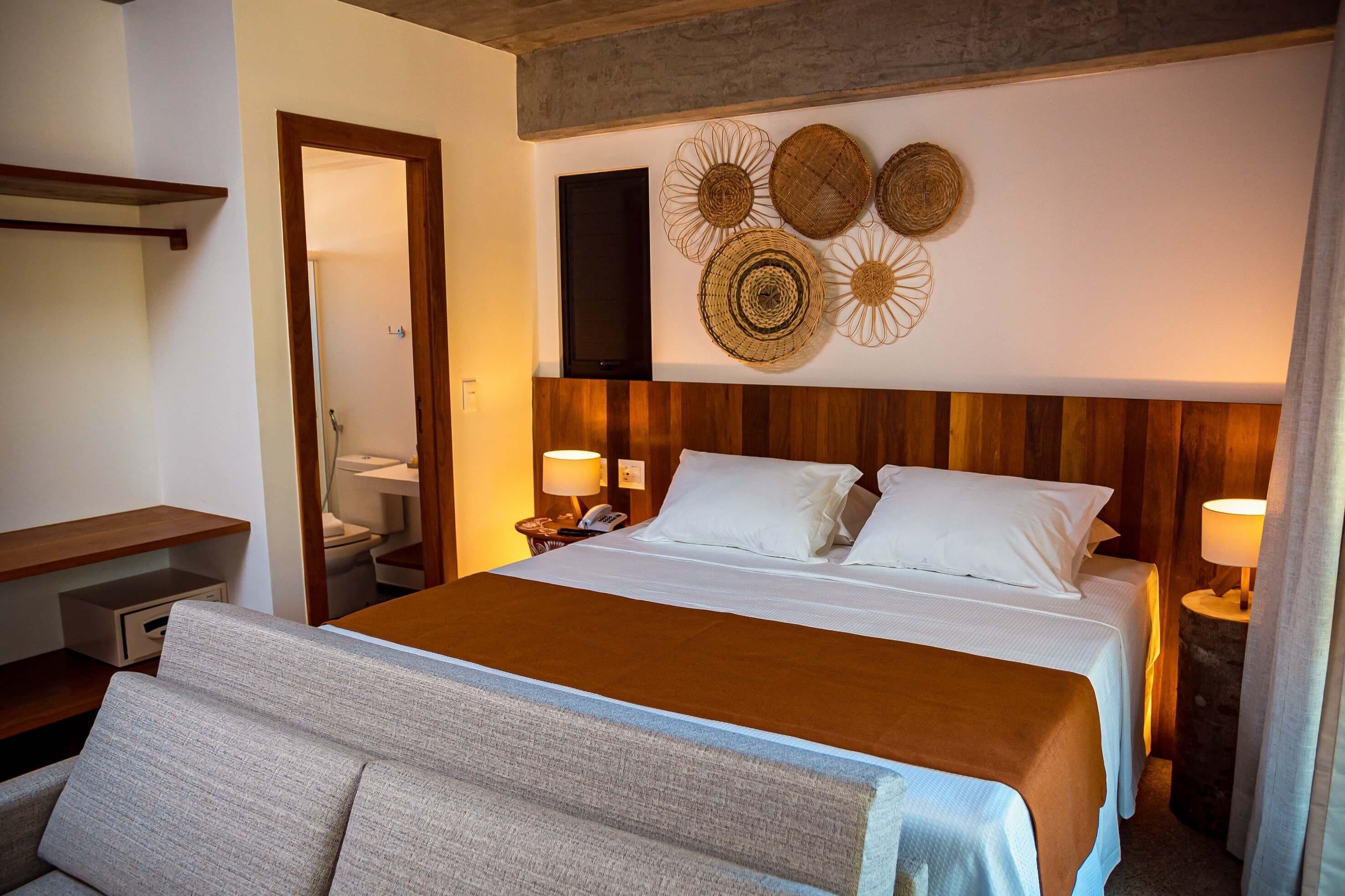 Una habitación de hotel con una cama, mesitas de noche, un cabecero de madera y decoración en la pared.