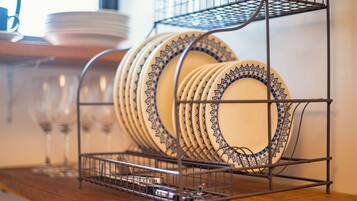A metal dish rack with plates and glasses on a wooden surface.