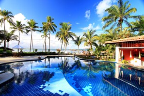 A swimming pool with clear blue tiles, surrounded by palm trees and a view of the ocean. - Aldeia do Mar Sensorial Hotel (Itacaré)