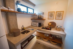 Una cocina con encimeras de granito, microondas, cafetera y diversos utensilios.