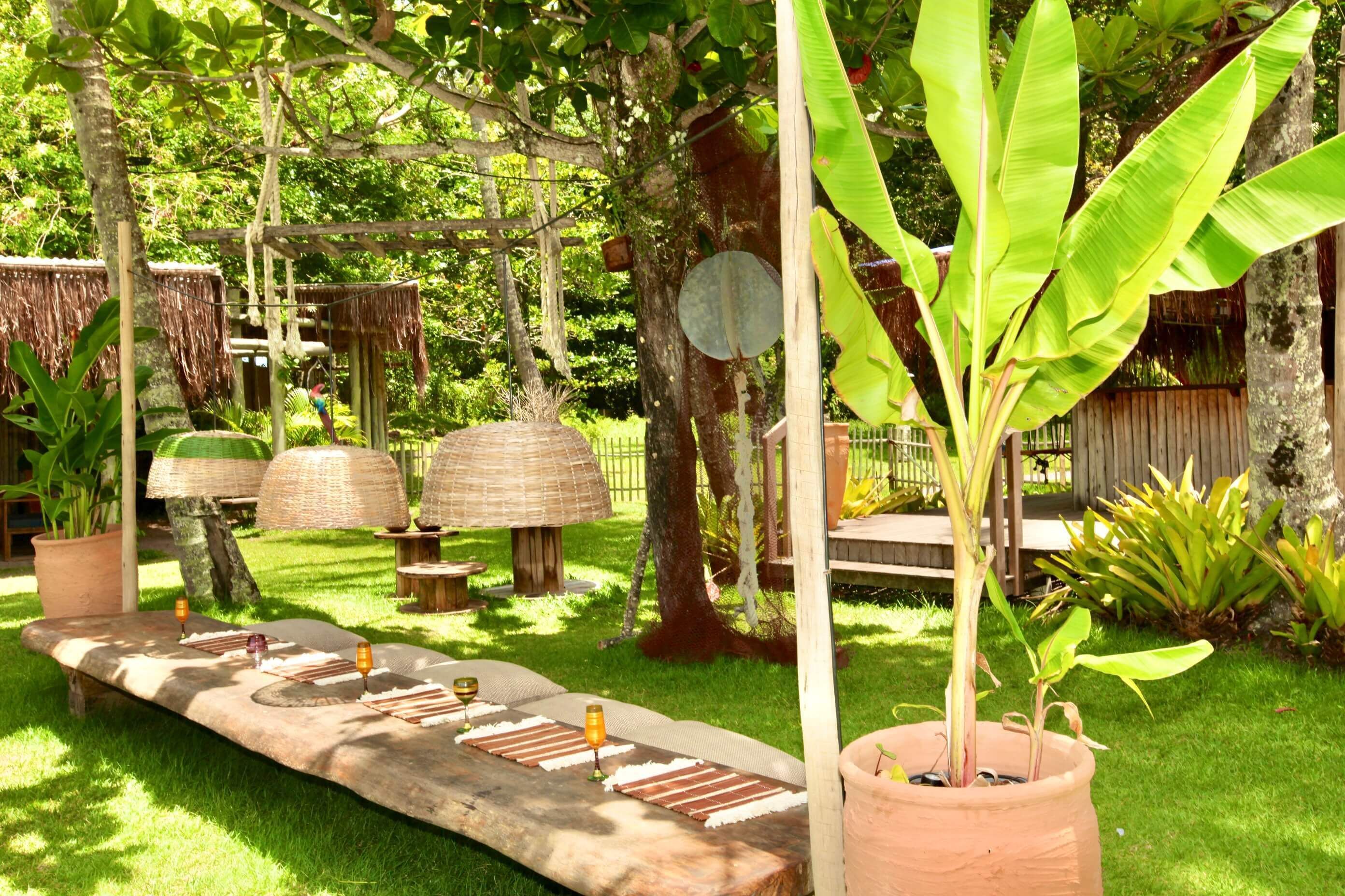 A garden area with a wooden bench, potted plants, and a thatched structure.
