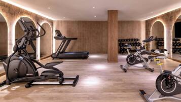 Un gimnasio con equipo cardiovascular, una cinta de correr y una pared de cascos.