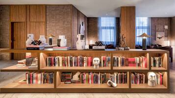 Una biblioteca moderna con estanterías de madera, suelo de mármol y un amplio ventanal con luz natural.