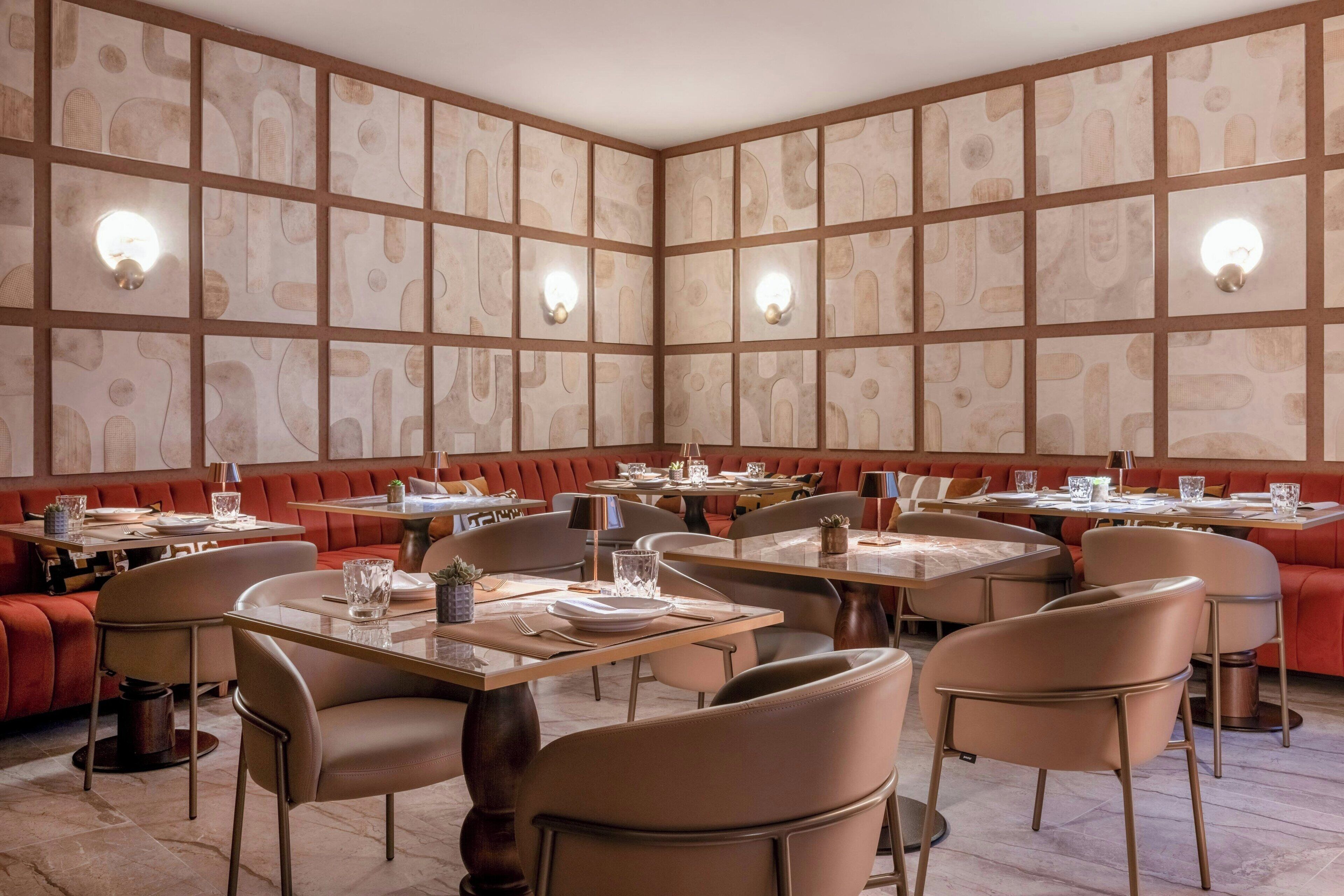 A restaurant with booths and tables, featuring a patterned wall and recessed lighting.