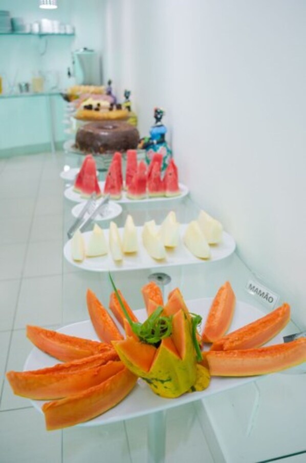 Un bufé con diversas frutas y postres.