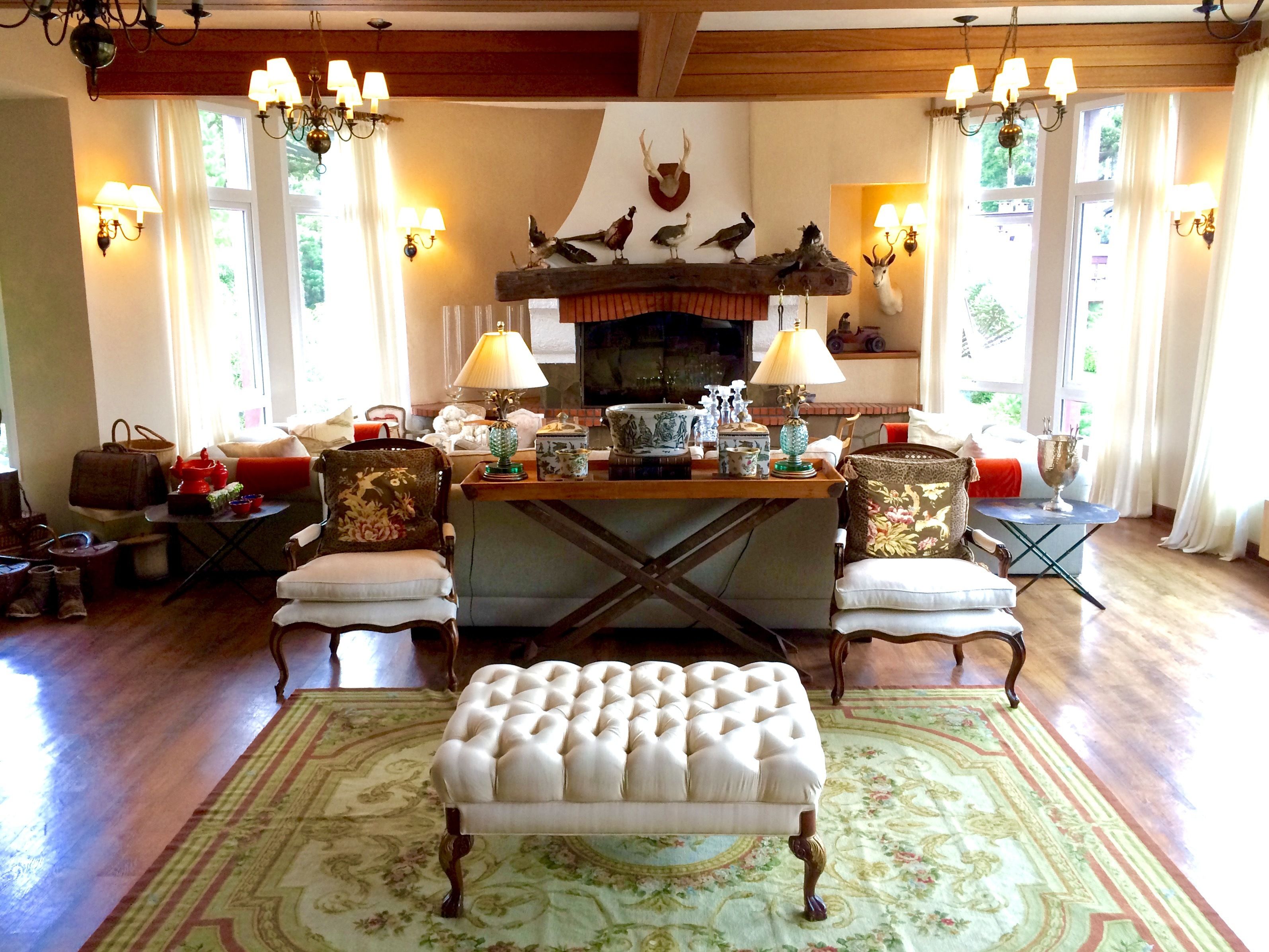 A traditional living room with a fireplace, wooden furniture, and decorative wall sconces.