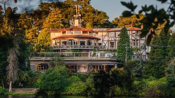 A lakeside building with a balcony overlooking the water, surrounded by trees.