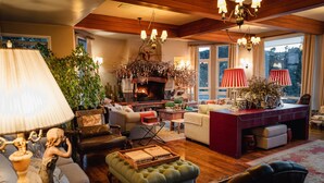 A cozy living room with a fireplace, comfortable seating, and a dining area with red lamps. - Estalagem St Hubertus (Gramado)