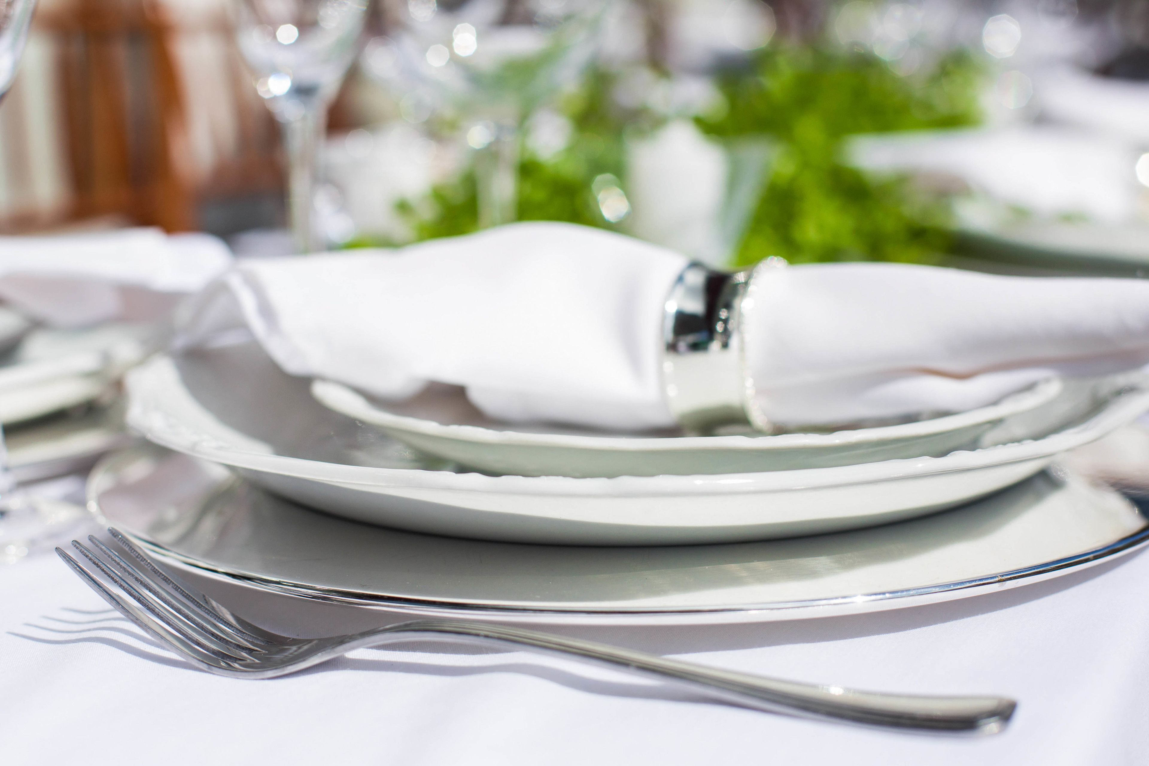 A neatly arranged dining table with a folded white napkin, a fork, and a plate.