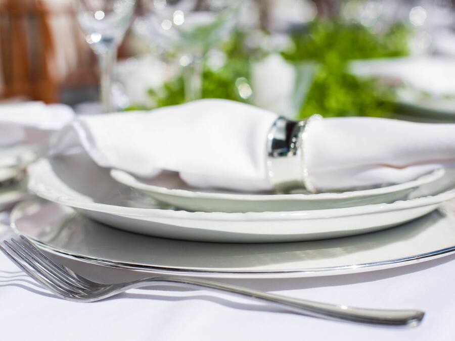 A neatly arranged dining table with a folded white napkin, a fork, and a plate.