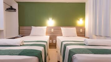 Quarto de hotel com duas camas, uma parede verde e uma cortina branca.