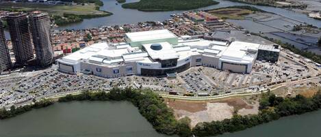 Un complejo arquitectónico moderno y extenso con varias edificaciones, rodeado por un estacionamiento y contiguo a un río.