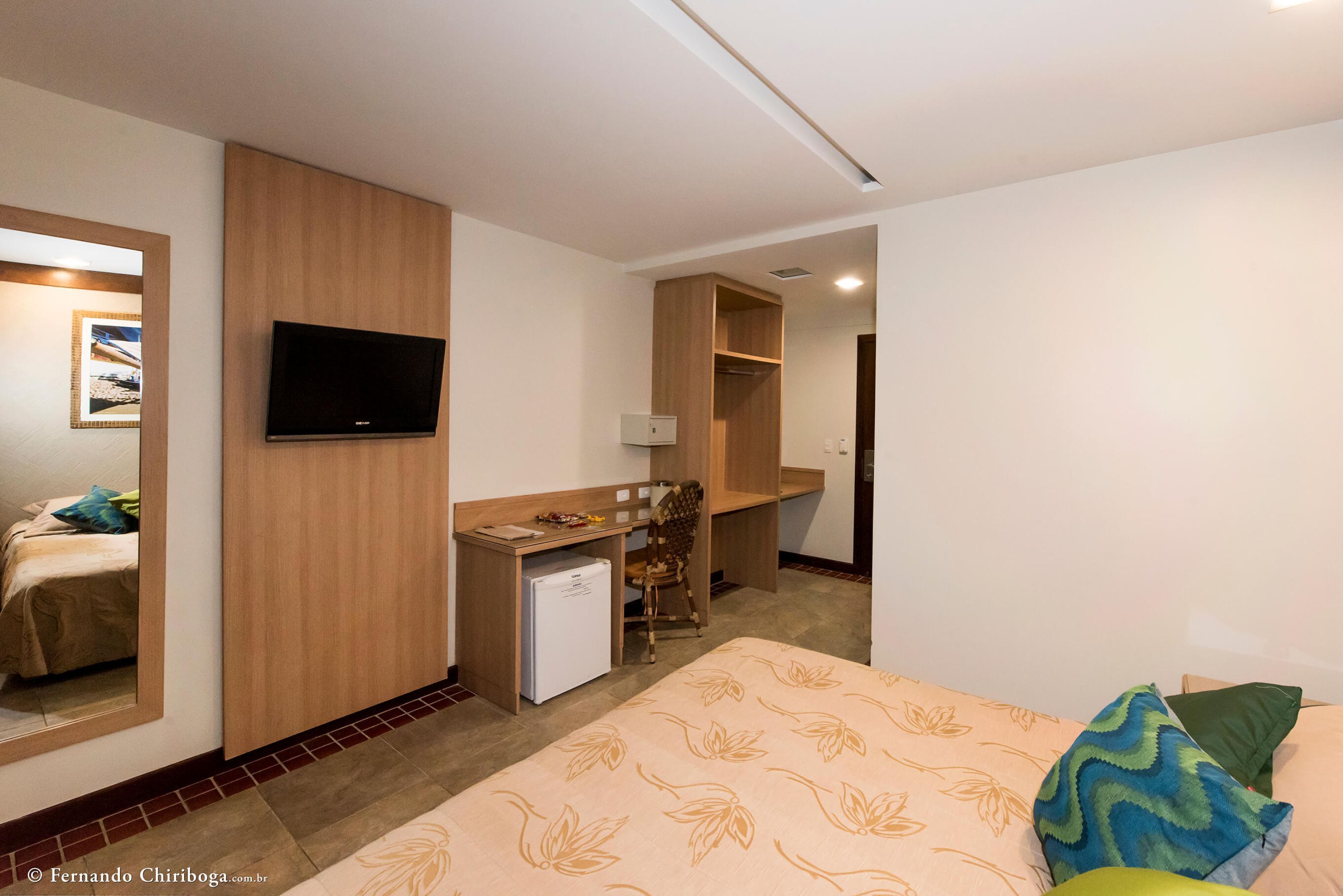 A hotel room with a bed, a desk, a television, and a wardrobe.