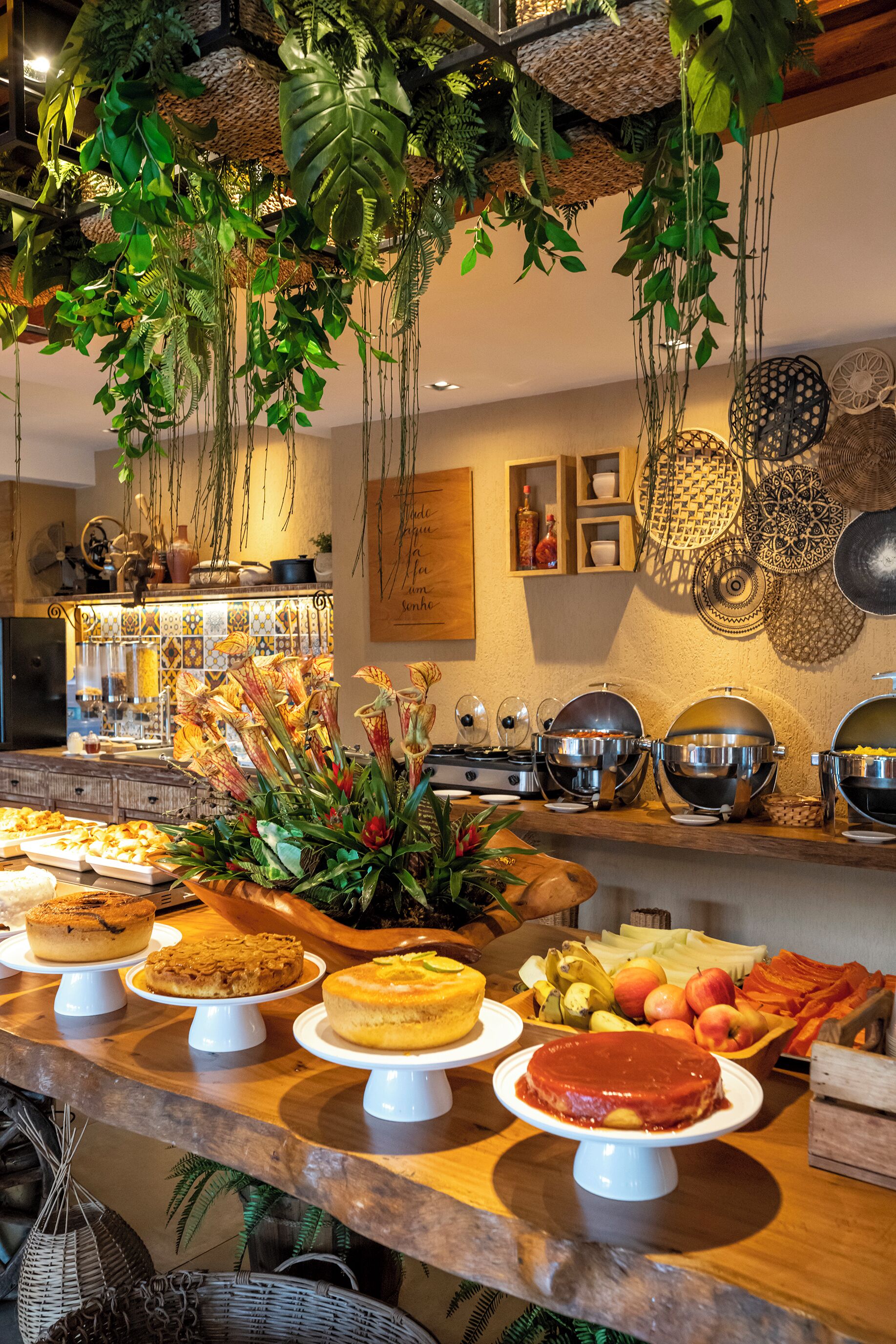 A buffet with various food items and decorative plants.