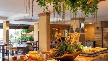 Un bufé con diversos alimentos y plantas colgantes en un amplio comedor.
