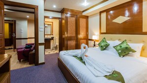 A hotel room with a neatly made bed, a desk with a chair, and a bathroom visible through an open door.