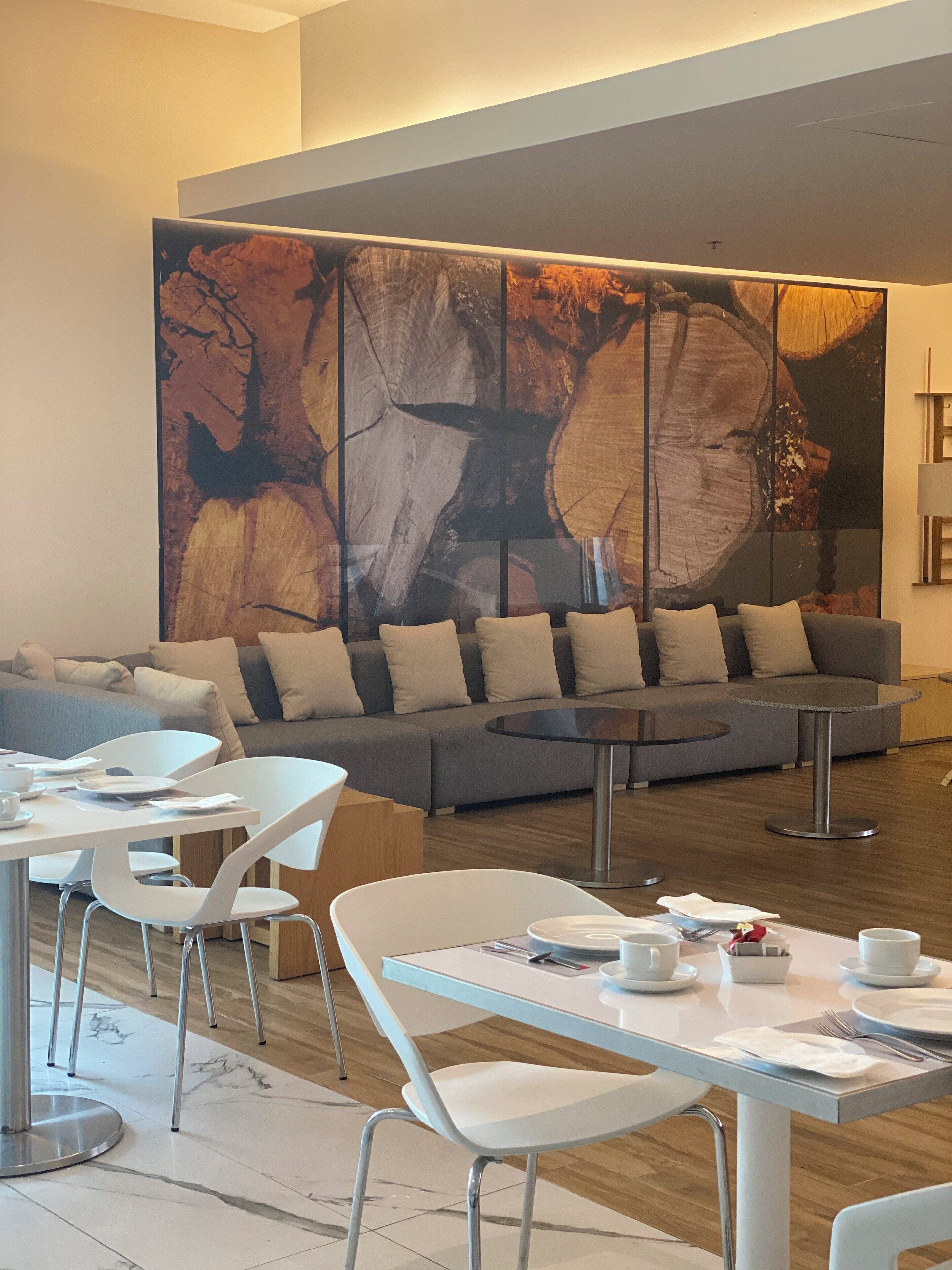 A modern lounge area with a large abstract painting, a grey sofa, and white chairs.