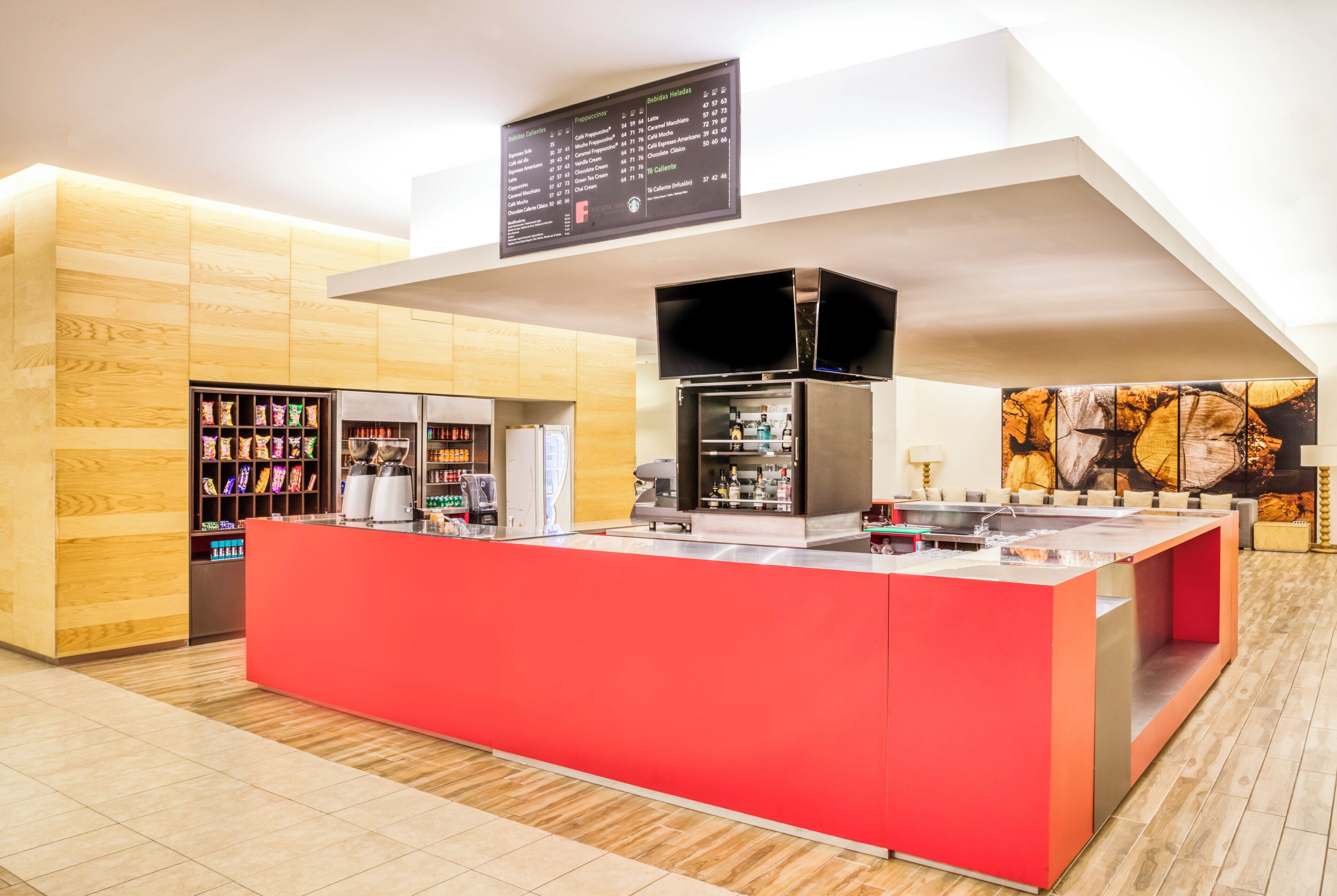 A modern kitchen area with a red counter, a coffee machine, and a menu board above.