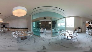 Un vestíbul d'hotel modern amb sòl de marbre, mobiliari blanc i grans finestres.