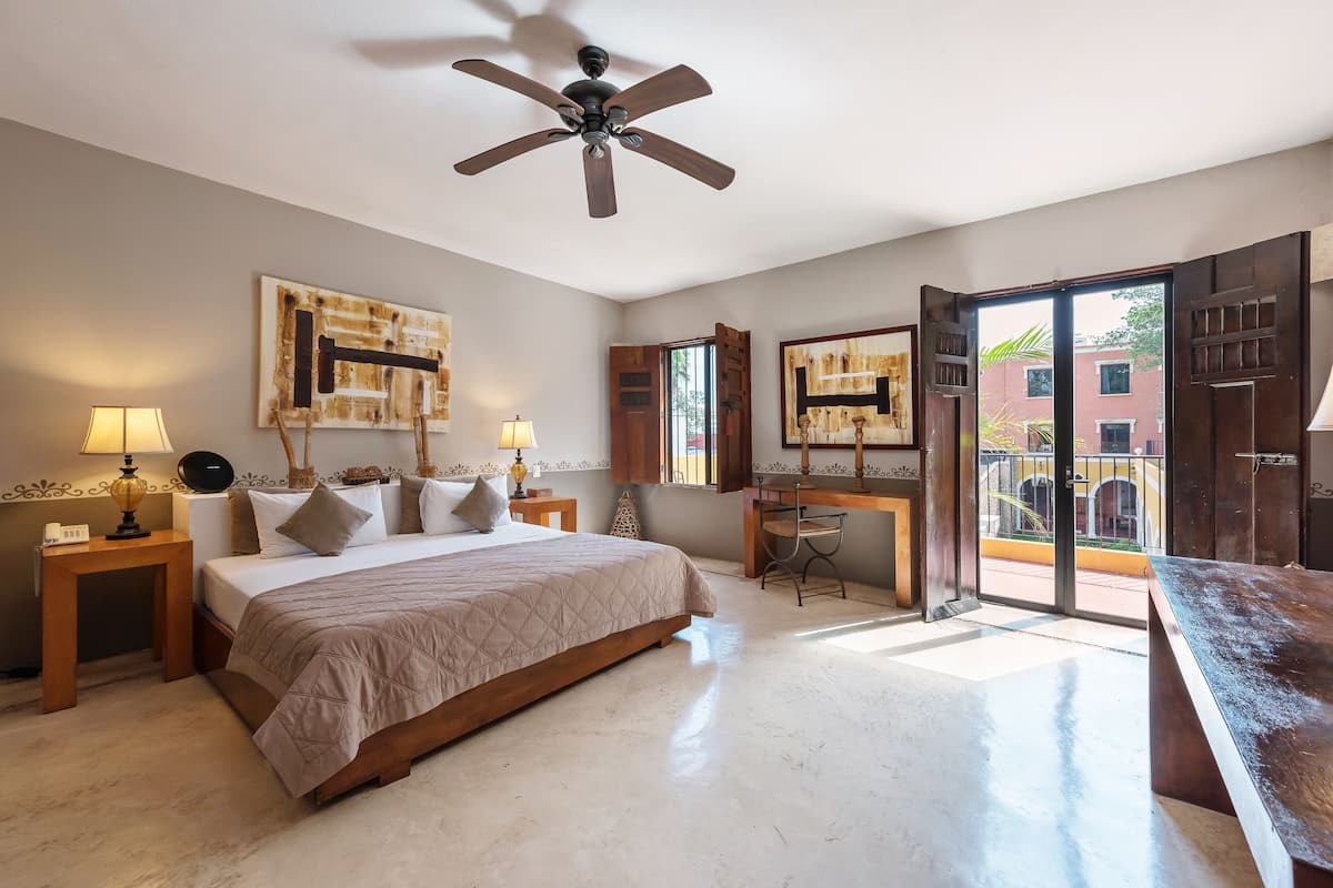 A spacious bedroom with a large bed, a desk, and a ceiling fan.