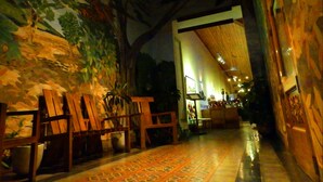 An interior corridor with wooden benches, a patterned floor, and a mural on the wall. - Mansión de Chocolate (Granada)
