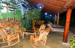 An outdoor seating area with wicker chairs and a table, surrounded by a mural of trees and plants. - Mansión de Chocolate (Granada)