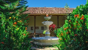 A garden with a fountain, surrounded by lush greenery and vibrant flowers. - Mansión de Chocolate (Granada)